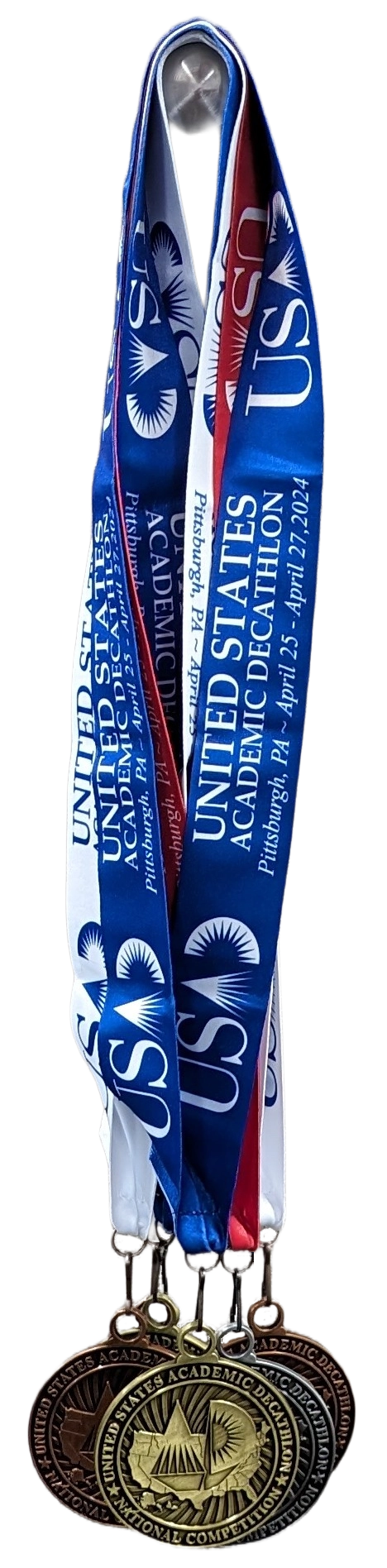 A set of United States Academic Decathlon (USAD) competition medals hanging from blue, red, and white ribbons. The medals are gold, silver, and bronze, representing different levels of achievement in the competition.